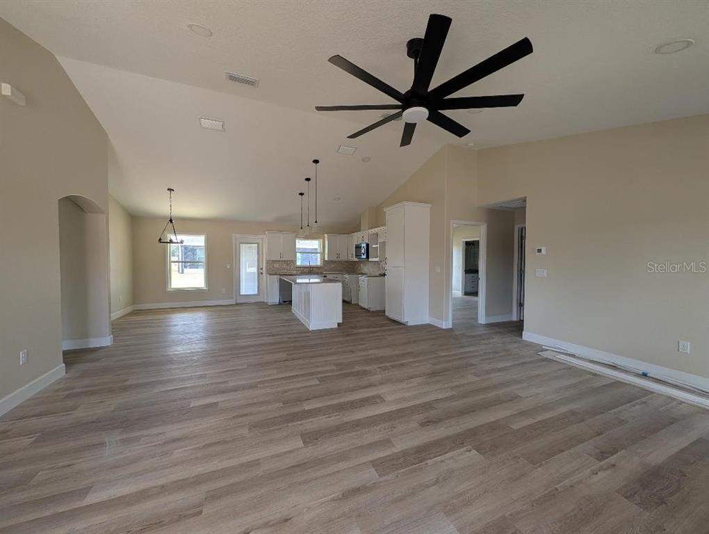 An open-concept living area features light wood-look flooring, a vaulted ceiling, and a kitchen island — 5441 CHESTNUT RIDGE ROAD, DADE CITY, FL