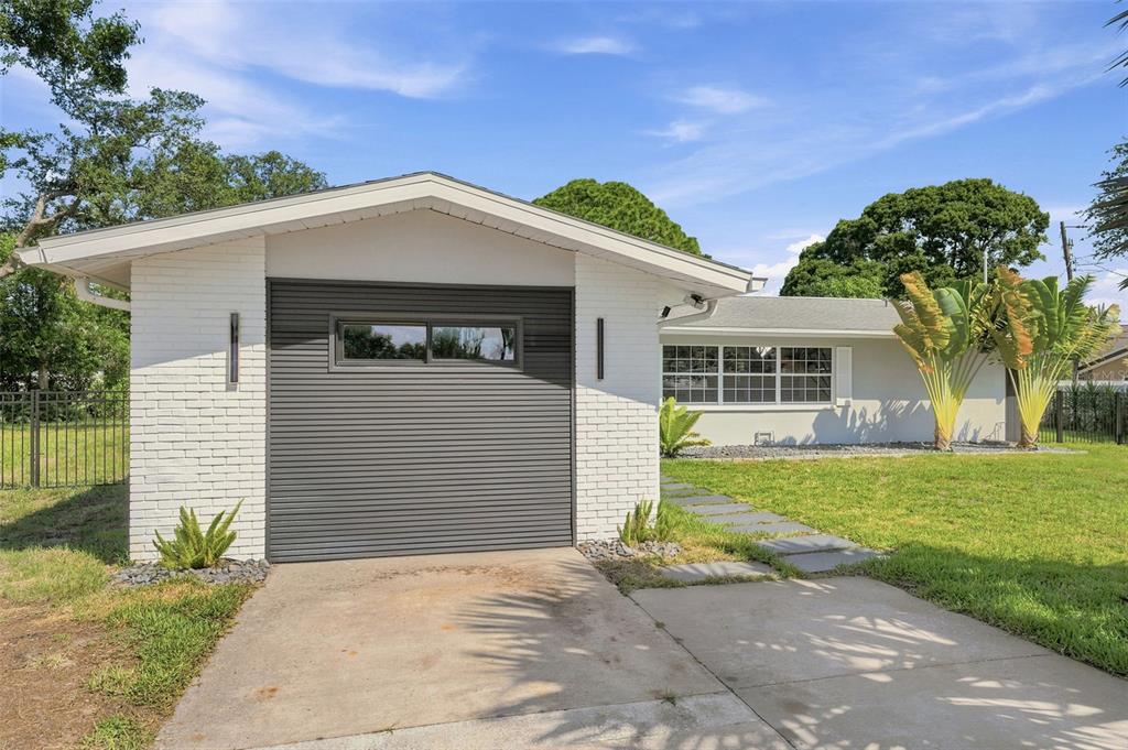 A white brick garage with a dark horizontal-slat door stands beside a single-story house — 14297 GENEVA DRIVE, LARGO, FL