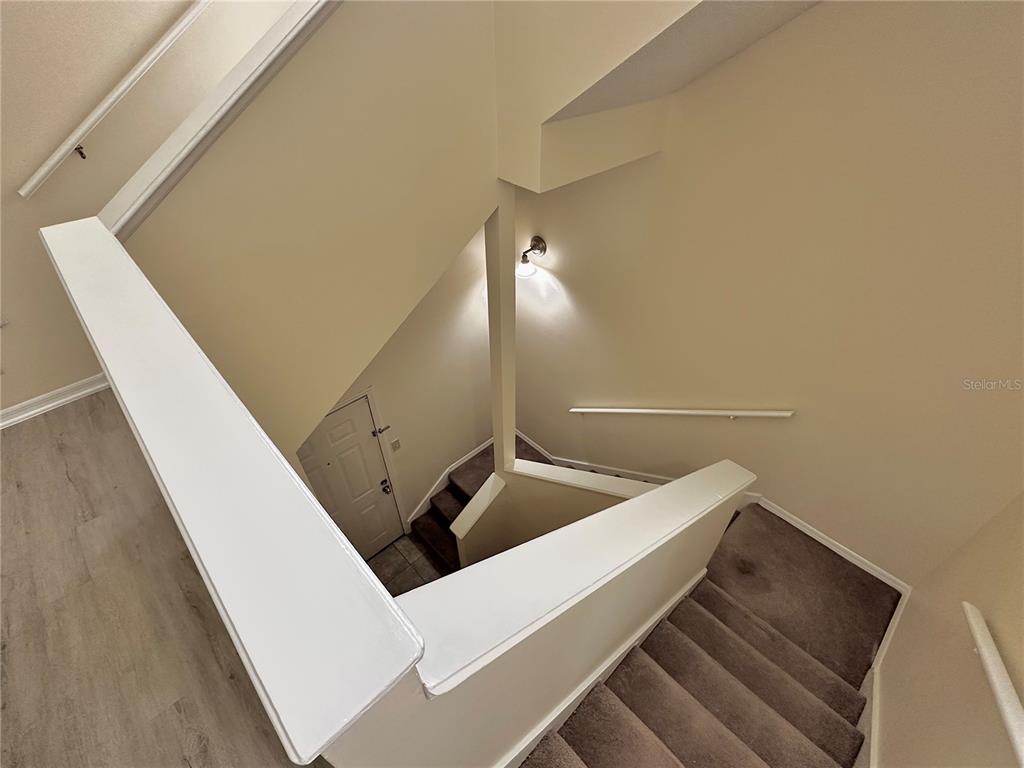 An elevated view shows a carpeted staircase leading down to a white front door — 6004 WESTGATE DRIVE UNIT 301, ORLANDO, FL