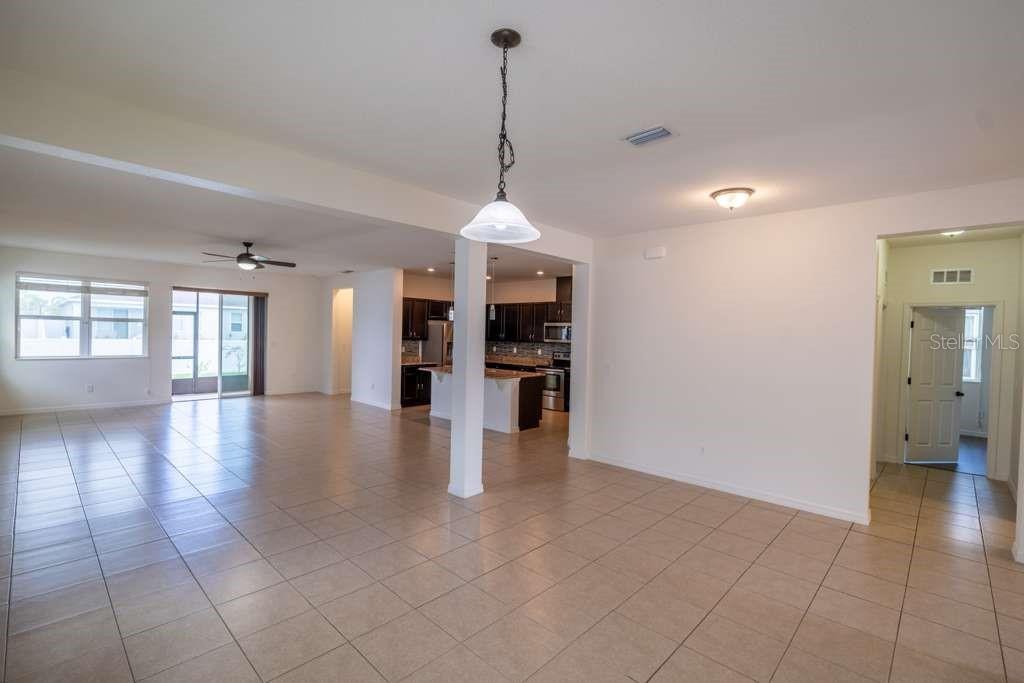 An open-concept living area features tile flooring, a kitchen island, and a hanging pendant light — 11517 PALMETTO SANDS COURT, TAMPA, FL