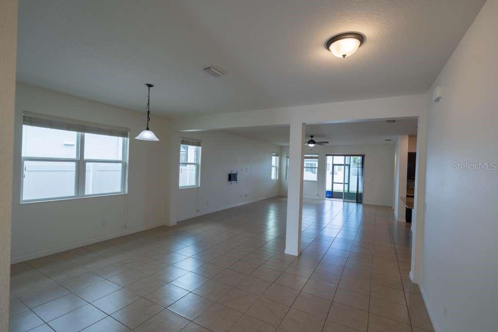 An open-concept living and dining area features light-colored tile flooring and neutral walls — 11517 PALMETTO SANDS COURT, TAMPA, FL