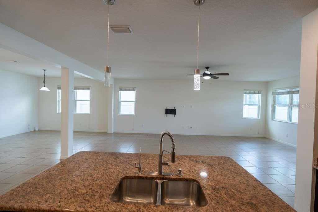 A kitchen island with a granite countertop and double sink overlooks an open living area — 11517 PALMETTO SANDS COURT, TAMPA, FL