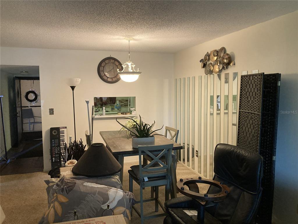 A dining area features a wooden table, chairs, a hanging light fixture, and mirrored wall panels — 4164 HERON WAY UNIT 208, BRADENTON, FL
