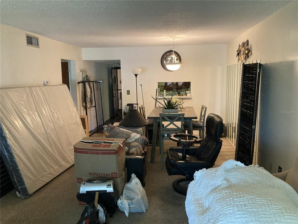 A dining area with a table and chairs is cluttered with boxes, furniture, and a mattress — 4164 HERON WAY UNIT 208, BRADENTON, FL
