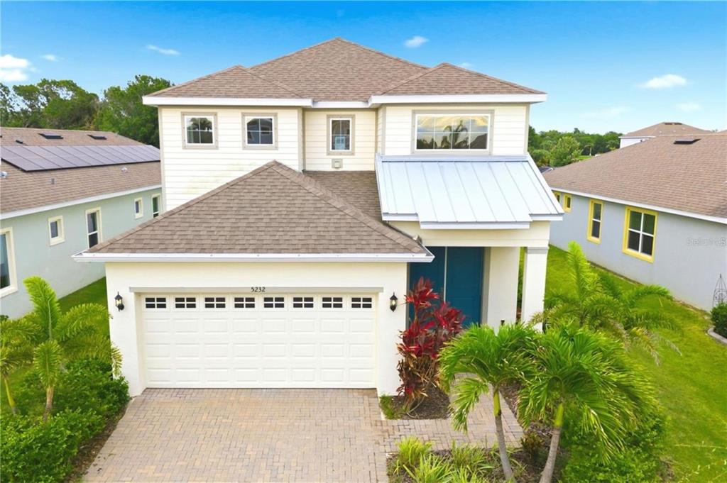 A two-story suburban house with a tan exterior, a two-car garage, and a metal roof — 5232 WISHING ARCH DRIVE, APOLLO BEACH, FL