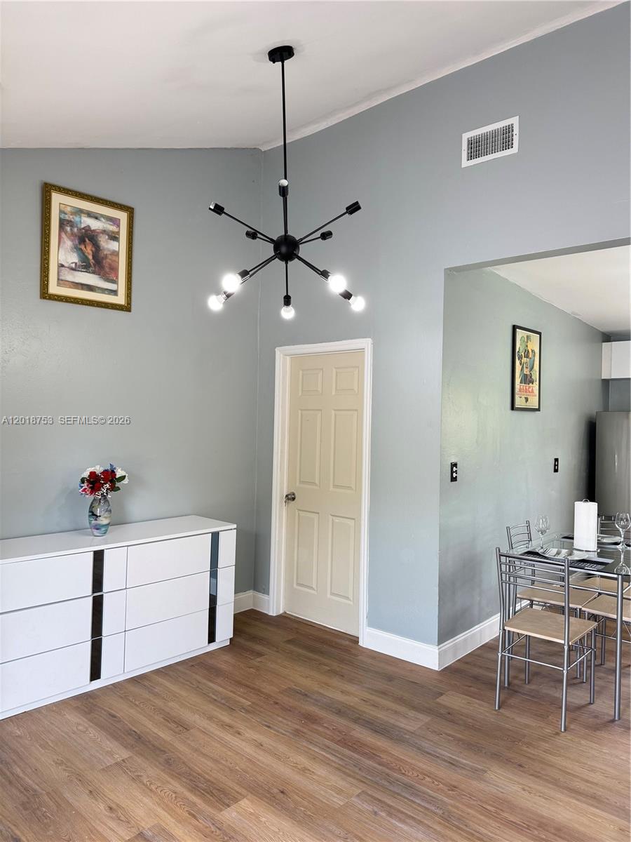 A dining area features a modern chandelier, a white dresser, and a metal dining set — 414 N 60th Way # 2, Hollywood FL 33024, HOLLYWOOD, FL