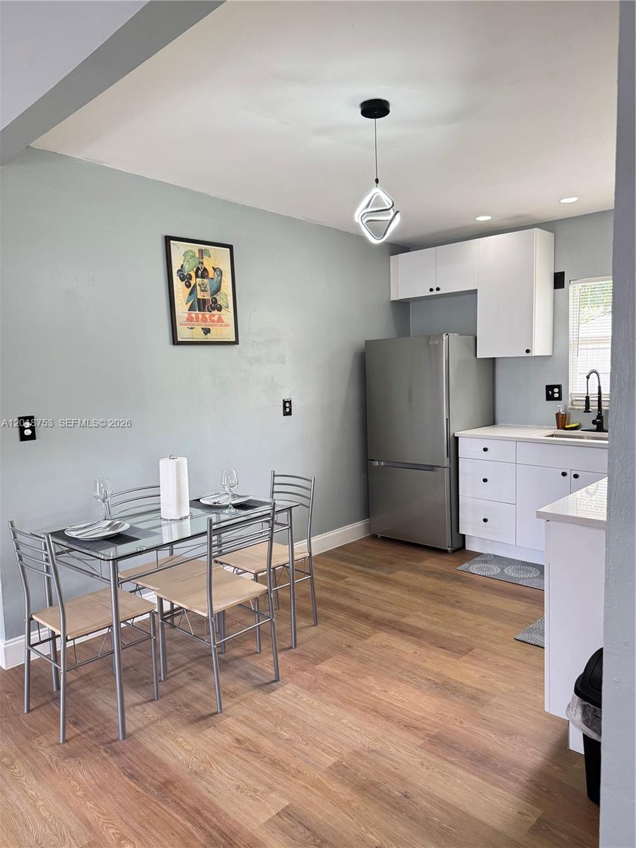 A dining area with a glass table and chairs sits adjacent to a small kitchen — 414 N 60th Way # 2, Hollywood FL 33024, HOLLYWOOD, FL