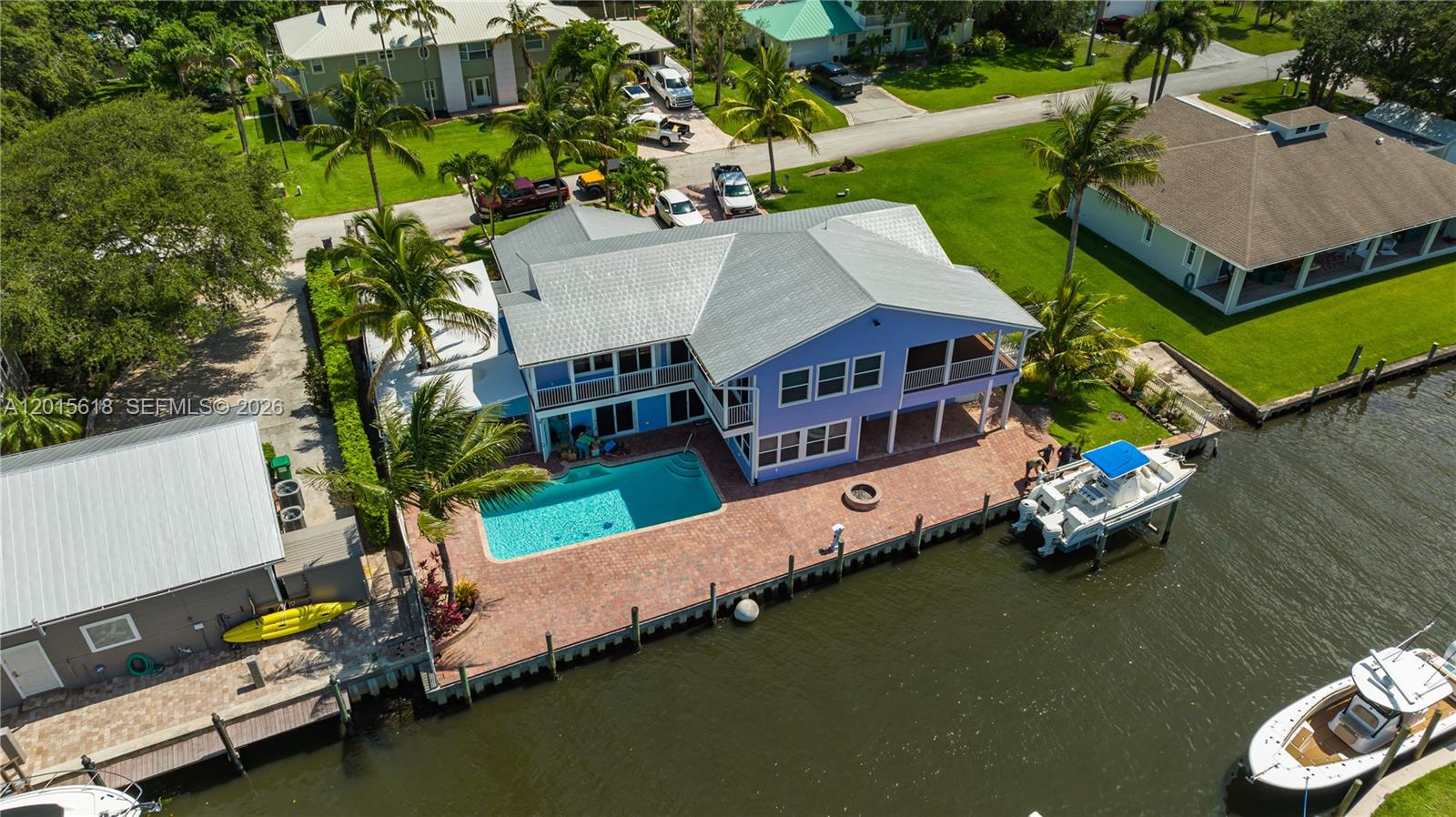 An aerial view shows a blue house with a pool and boat dock on a canal — 474 Peninsula Dr, Fort Pierce FL 34946, FORT PIERCE, FL