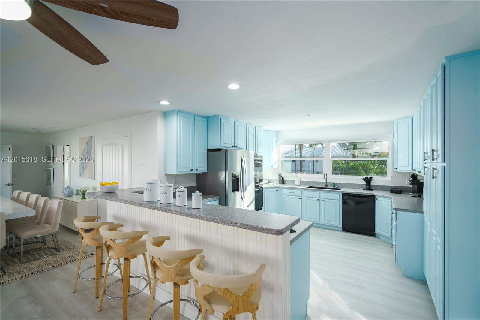 A kitchen features light blue cabinets, gray countertops, a breakfast bar, and stainless steel appliances — 474 Peninsula Dr, Fort Pierce FL 34946, FORT PIERCE, FL