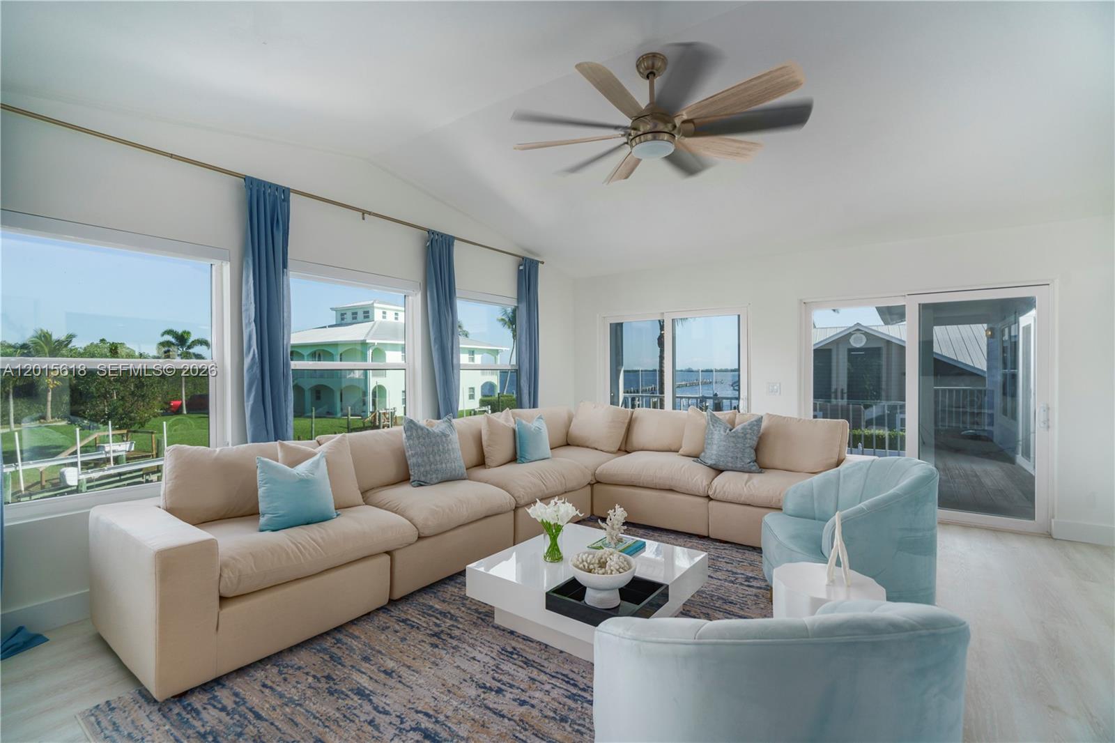 A living room features a large beige sectional, light blue armchairs, and floor-to-ceiling windows — 474 Peninsula Dr, Fort Pierce FL 34946, FORT PIERCE, FL