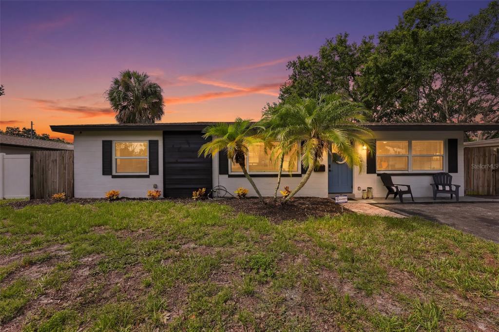 A single-story house with a white exterior, black shutters, and a blue front door — 716 75TH AVENUE N, ST PETERSBURG, FL