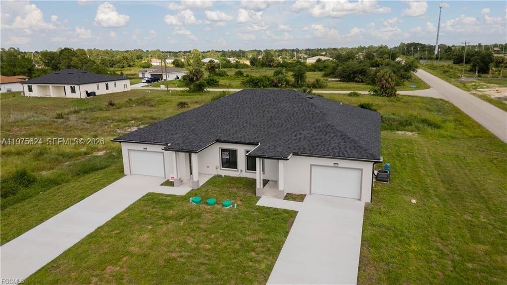 An aerial view of a single-story house with two garages and a dark shingled roof — 1171 countess ave, Lehigh Acres FL 33974, LEHIGH ACRES, FL