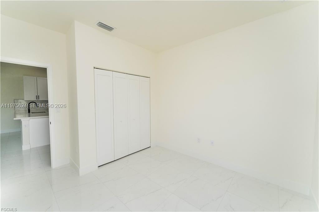 A room with white walls, white tile flooring, and a white bi-fold closet door — 1171 countess ave, Lehigh Acres FL 33974, LEHIGH ACRES, FL