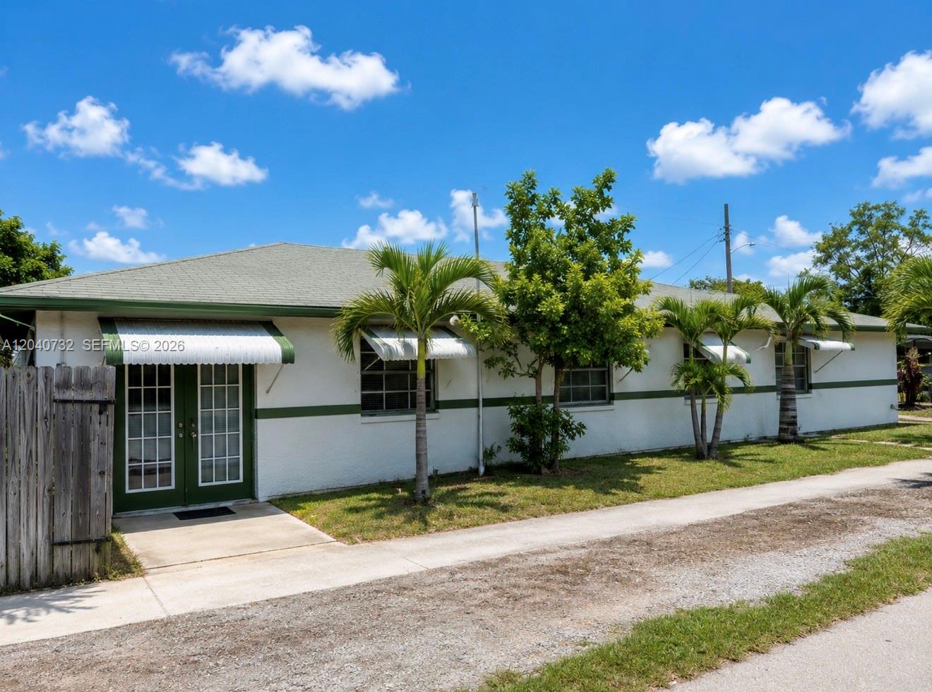 A single-story white house with green trim and palm trees under a blue sky — 141 SW 2nd St, Deerfield Beach FL 33441, DEERFIELD BEACH, FL