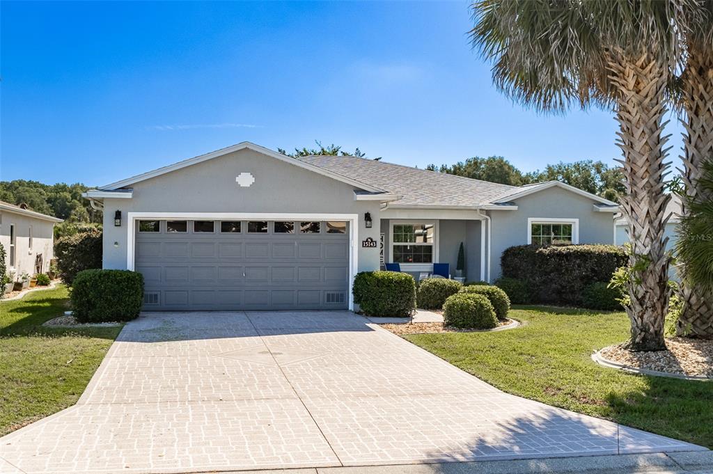 A single-story house with a gray garage, light-colored stucco walls, and a paved driveway — 15143 SW 14TH AVENUE ROAD, OCALA, FL
