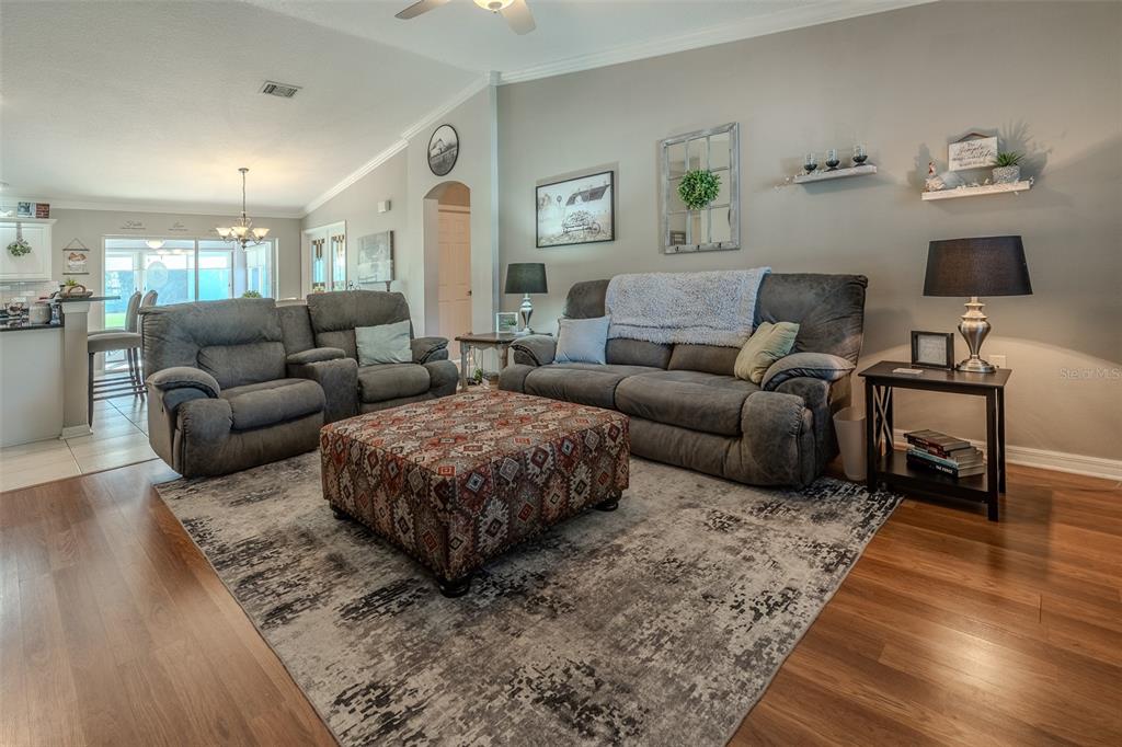 A living room features grey reclining sofas, a patterned ottoman, and a large area rug — 15143 SW 14TH AVENUE ROAD, OCALA, FL