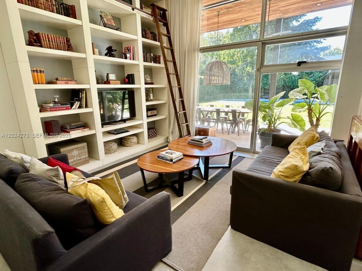 A living room features built-in bookshelves, a rolling ladder, two round coffee tables, and floor-to-ceiling windows — MA