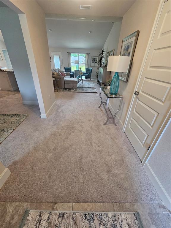 A carpeted hallway leads to a living room with a sofa and two blue chairs — 133 SW BELLFLOWER DRIVE, LAKE CITY, FL