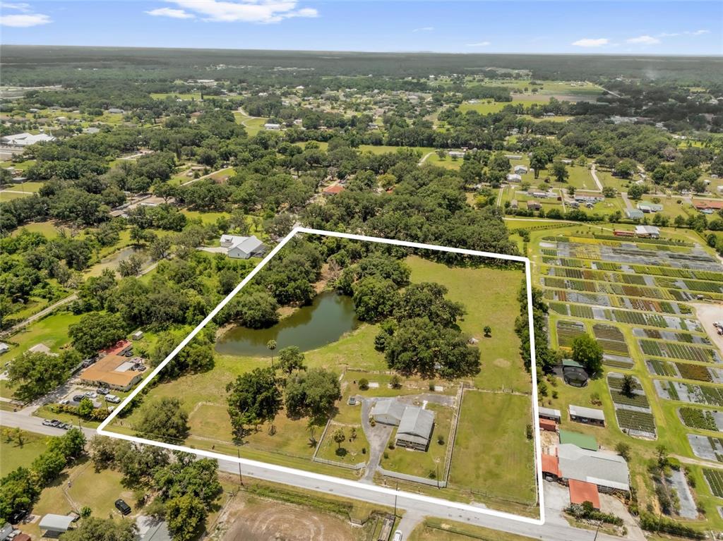 An aerial view shows a fenced property with a house, a pond, and surrounding trees — 3101 MEDULLA ROAD, PLANT CITY, FL