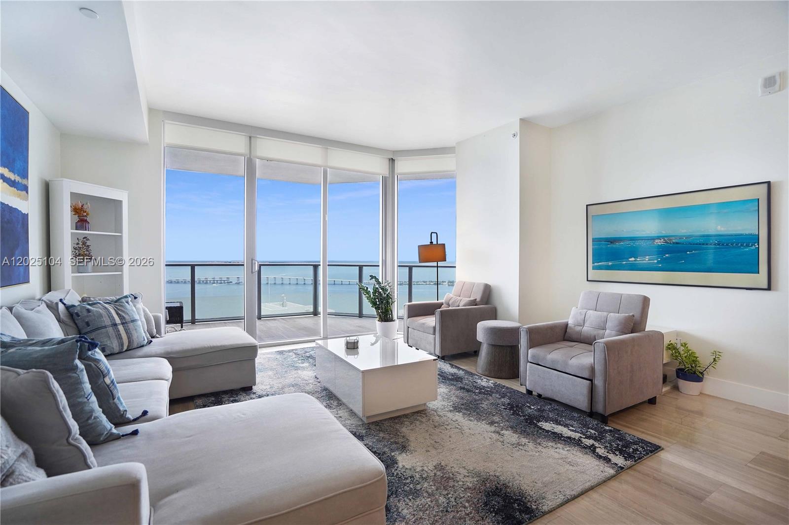 A living room features a sectional sofa, armchairs, a coffee table, and floor-to-ceiling windows overlooking water — 1300 Brickell Bay Dr # 3402, Miami FL 33131, MIAMI, FL