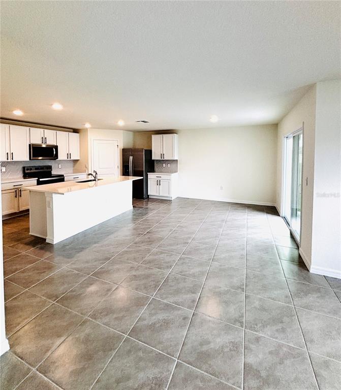 A kitchen with white cabinets, a central island, and gray tile flooring — 1894 NW 247TH DRIVE, NEWBERRY, FL