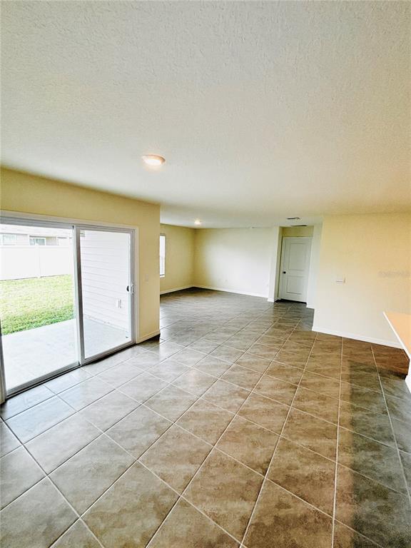 An open-concept room features tile flooring, a sliding glass door, and a white interior door — 1894 NW 247TH DRIVE, NEWBERRY, FL