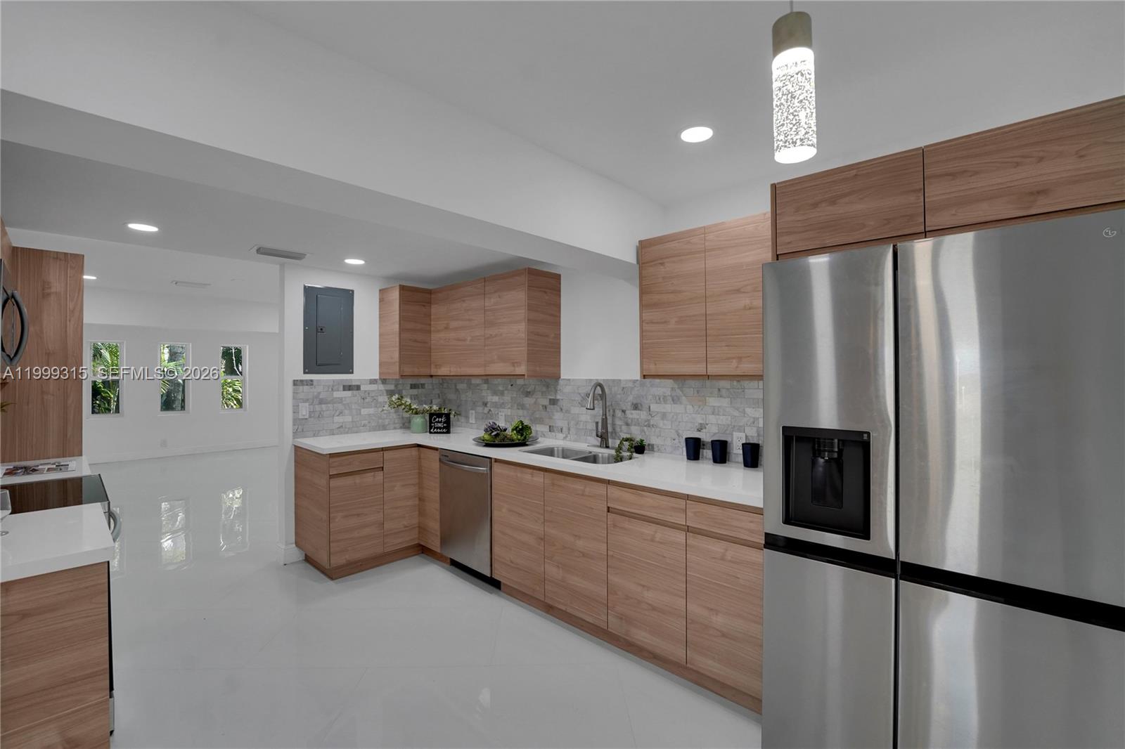 A modern kitchen features light wood cabinets, white countertops, stainless steel appliances, and tile flooring — FORT LAUDERDALE, FL