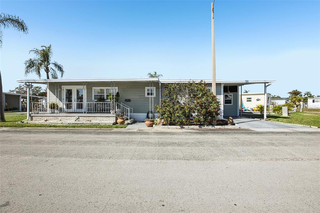 A single-story mobile home with light green siding, a front porch, and a carport — 82123 B STREET N UNIT 123, PINELLAS PARK, FL