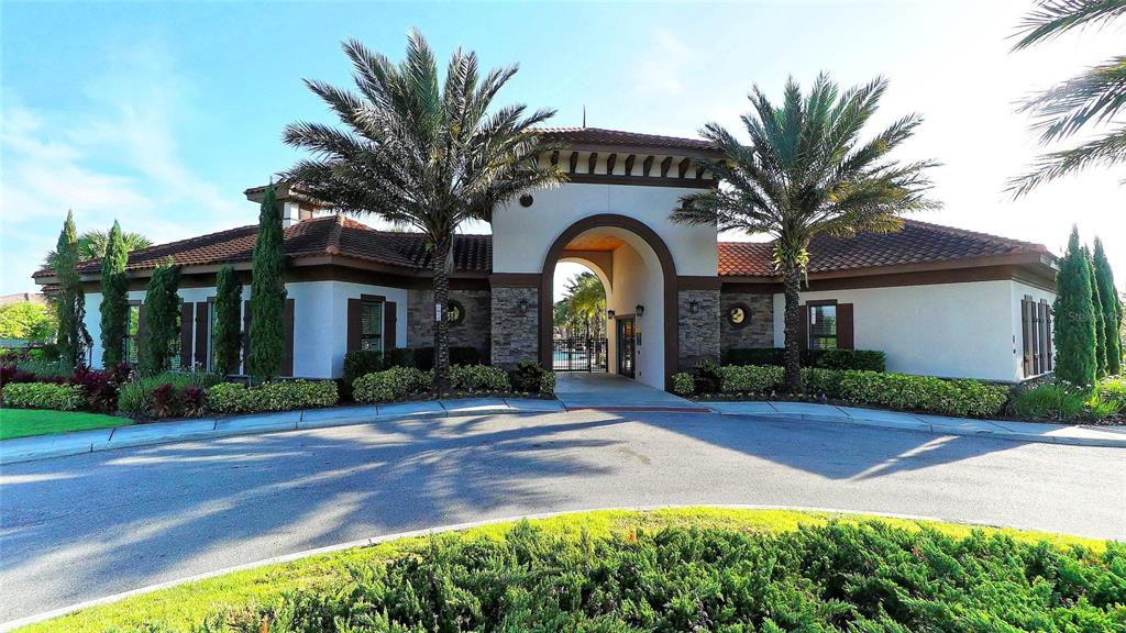 A Mediterranean-style community clubhouse exterior features a central arched entryway and two palm trees — 1307 OAK CREST STREET, DAVENPORT, FL