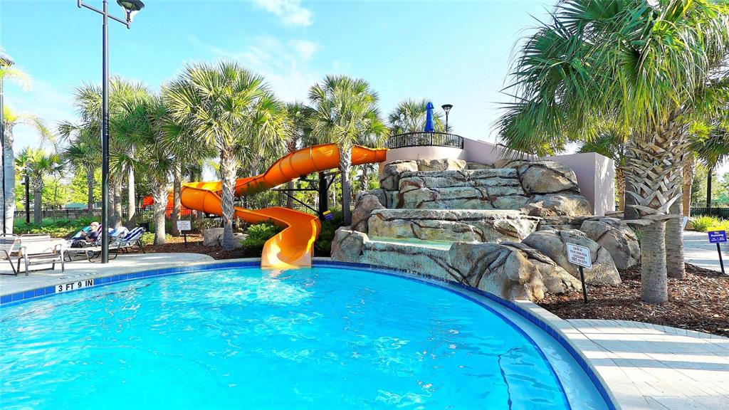 A swimming pool features a large orange water slide and a decorative rock waterfall — 1307 OAK CREST STREET, DAVENPORT, FL