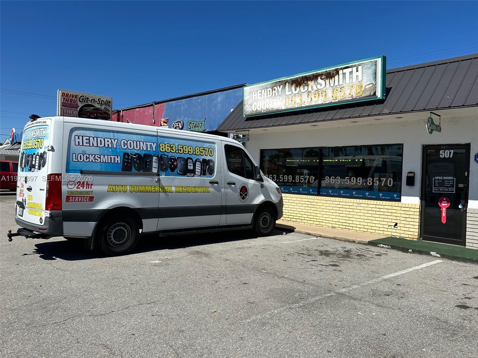 A white locksmith van is parked in front of a commercial building with a sign — 507 E Sugarland Hwy, Clewiston FL 33440, CLEWISTON, FL