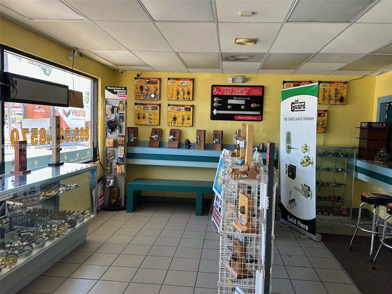 A commercial locksmith shop interior features display cases, wall-mounted hardware, and tiled flooring — 507 E Sugarland Hwy, Clewiston FL 33440, CLEWISTON, FL