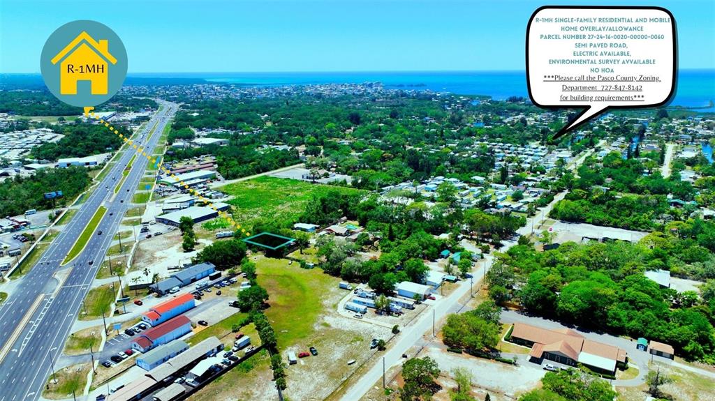 This aerial view shows a plot of land near a highway and residential area — TBD LOT 6 SCAMP DRIVE, HUDSON, FL