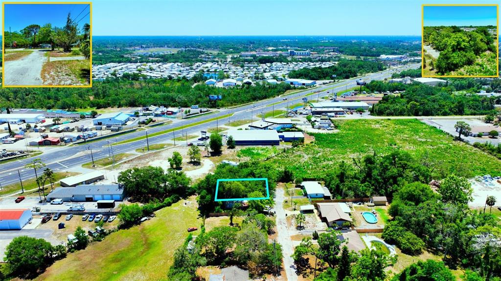An aerial view shows a wooded lot outlined in blue near a highway and buildings — TBD LOT 6 SCAMP DRIVE, HUDSON, FL