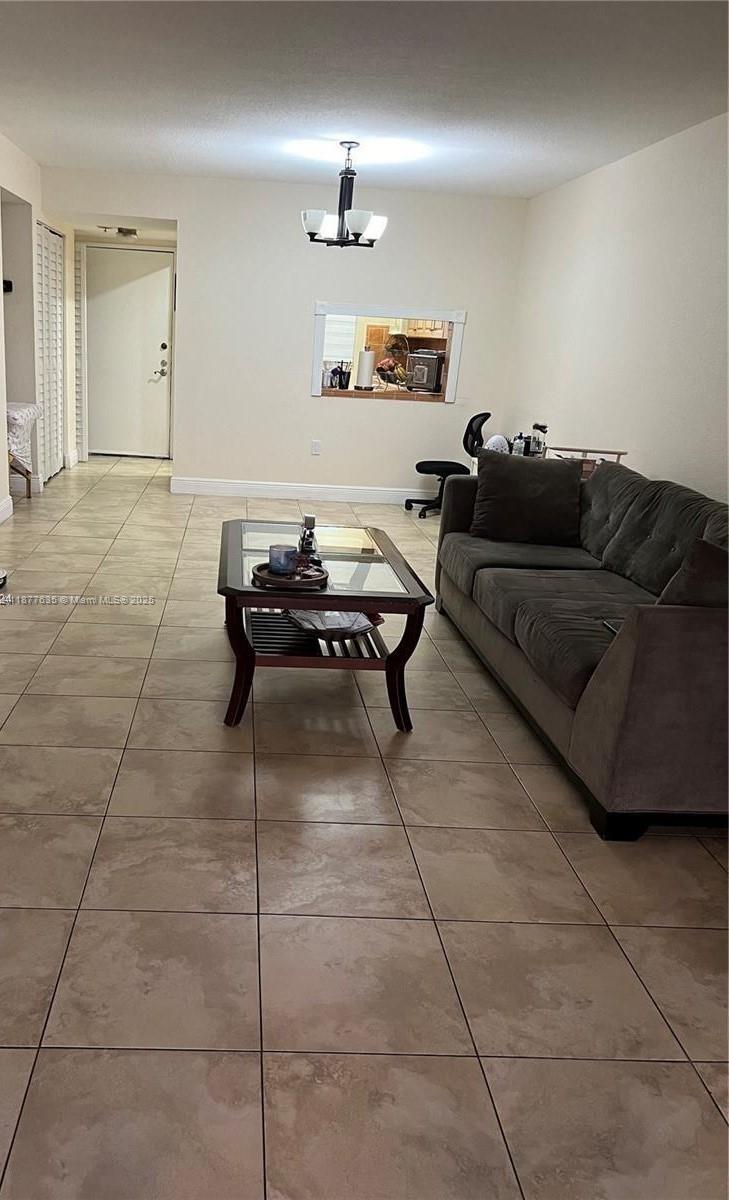 A living room features beige tile flooring, a dark gray sofa, and a glass coffee table — 8875 Fontainebleau Blvd # 203, Miami FL 33172, MIAMI, FL