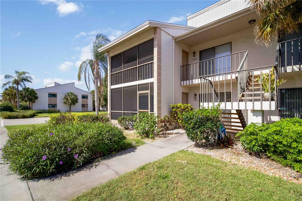 Exterior view of a two-story apartment building with a screened-in porch and outdoor staircase — 5476 SWIFT ROAD UNIT 19, SARASOTA, FL
