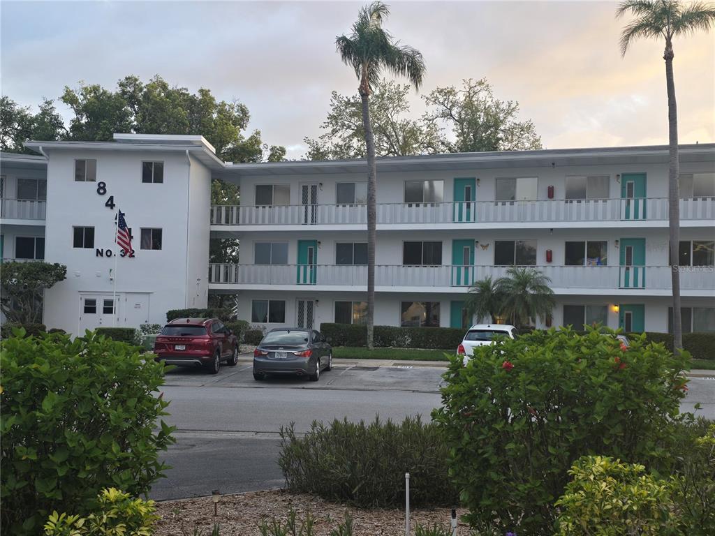 A three-story white apartment building features exterior walkways and a parking lot in front — 8454 111TH STREET UNIT 209, SEMINOLE, FL