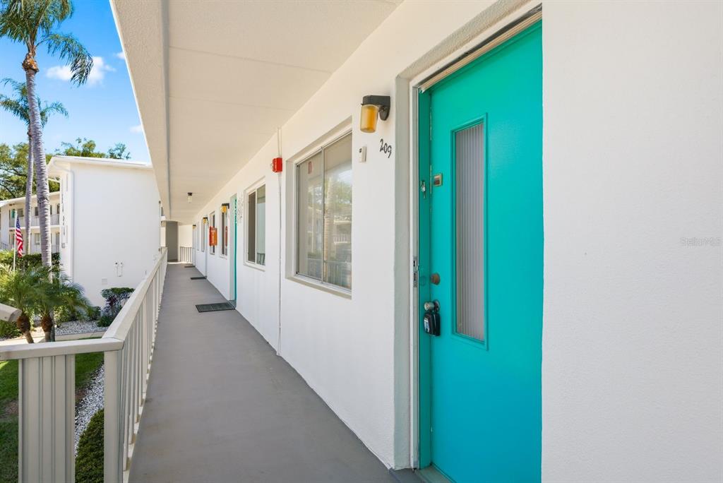 An exterior walkway leads to a bright turquoise apartment door labeled 209 — 8454 111TH STREET UNIT 209, SEMINOLE, FL