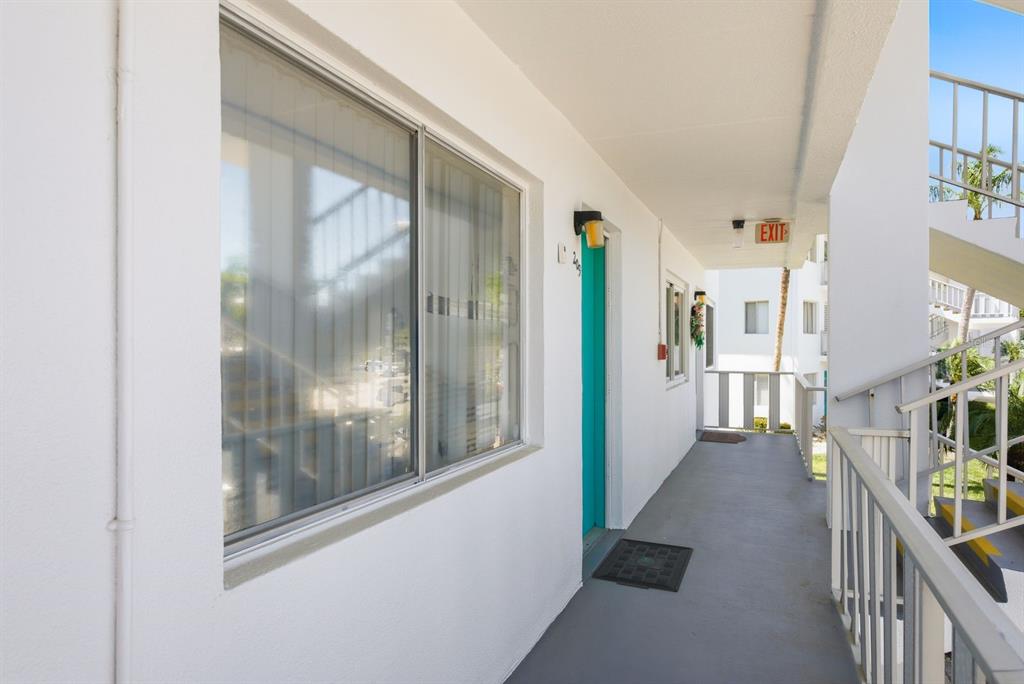 An exterior walkway leads to a teal apartment door with a large window nearby — 8454 111TH STREET UNIT 209, SEMINOLE, FL