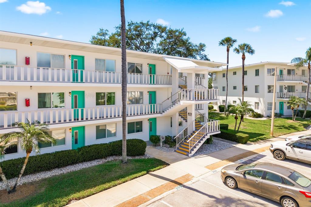 An exterior view of a multi-story apartment building with teal doors and outdoor staircases — 8454 111TH STREET UNIT 209, SEMINOLE, FL