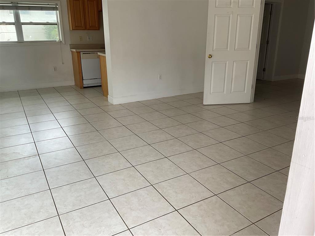 A room with light-colored tile flooring, a white door, and a partial view of a kitchen — 2121 LAKEVIEW DRIVE, SEBRING, FL