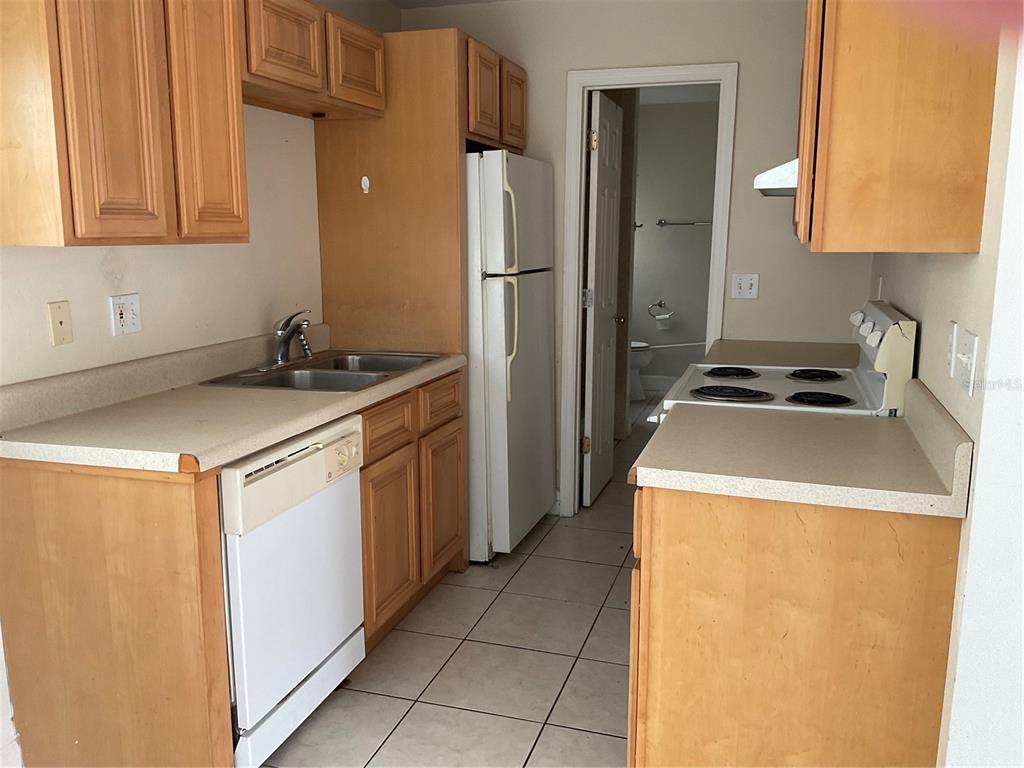 A kitchen with light wood cabinets, white appliances, a double sink, and tiled flooring — 2121 LAKEVIEW DRIVE, SEBRING, FL