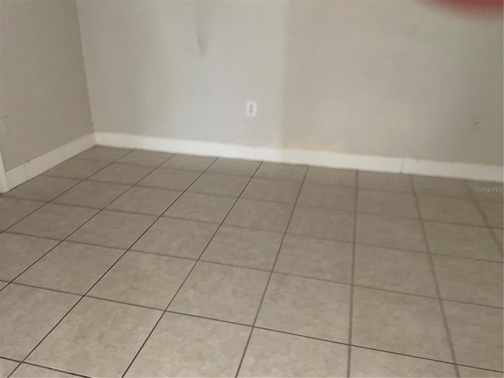 An empty room features light gray walls, white baseboards, and beige square floor tiles — 2121 LAKEVIEW DRIVE, SEBRING, FL
