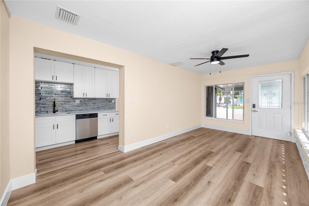 A room with light-colored walls, wood-look flooring, a ceiling fan, and an adjacent kitchenette — 504 79TH AVENUE, ST PETERSBURG, FL
