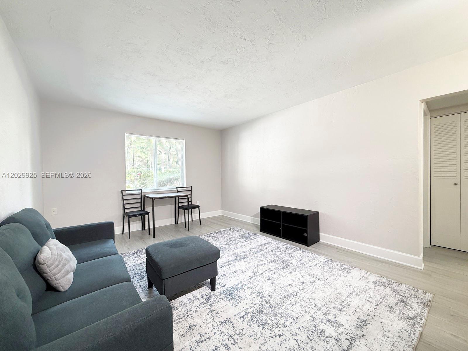 A living room features a gray sofa, a matching ottoman, and a small dining set — 8601 SW 68 CT # 5, Pinecrest FL 33156, PINECREST, FL