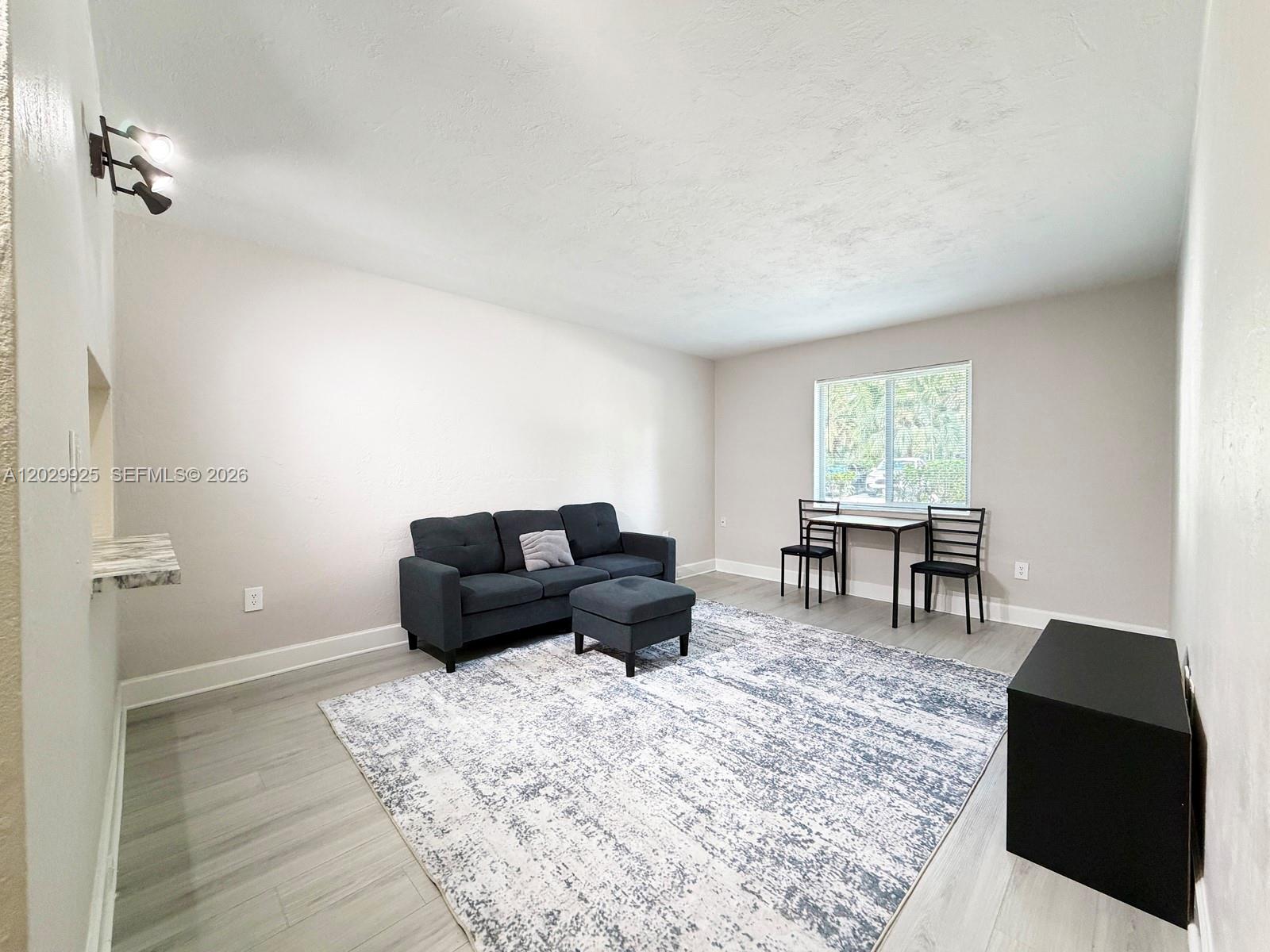 A living room features light gray flooring, a dark sofa with ottoman, and a dining set — 8601 SW 68 CT # 5, Pinecrest FL 33156, PINECREST, FL