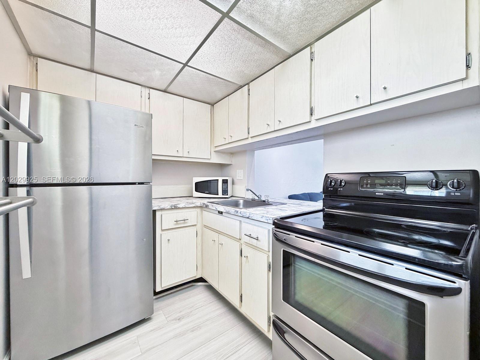 A kitchen features light-colored cabinets, stainless steel appliances, and a drop ceiling — 8601 SW 68 CT # 5, Pinecrest FL 33156, PINECREST, FL