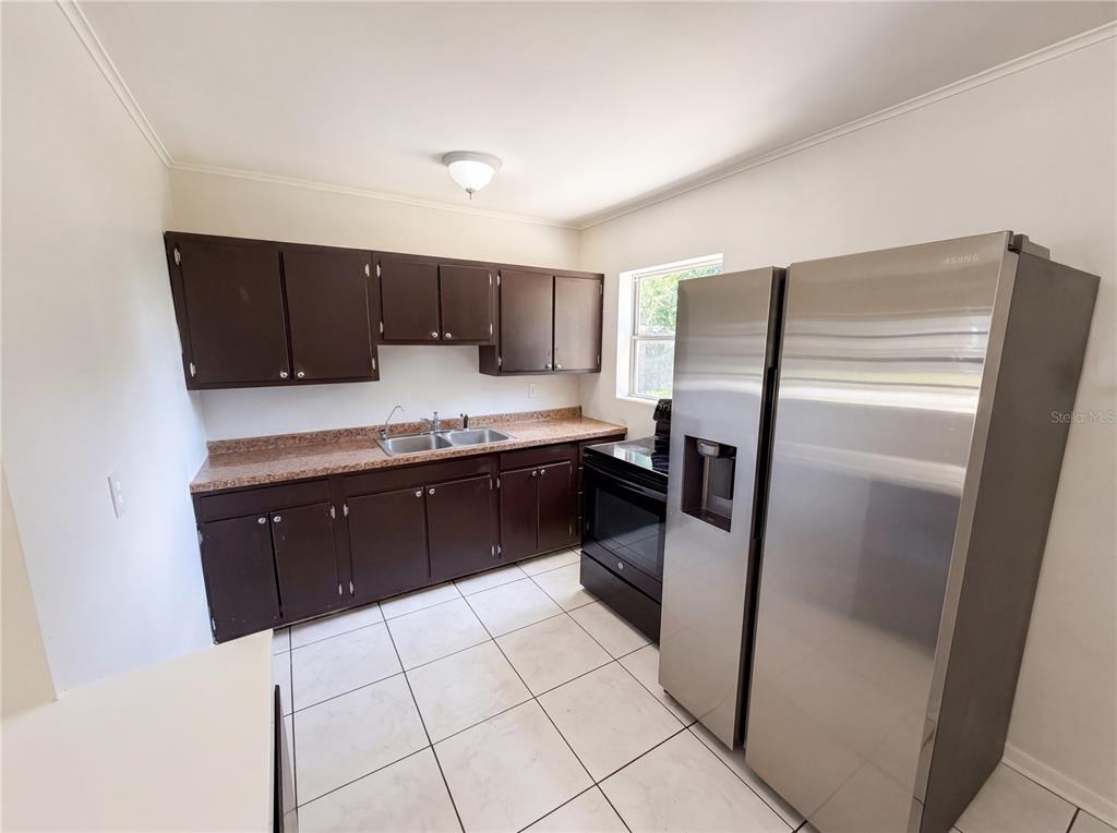 A kitchen features dark brown cabinets, a speckled countertop, white tile floors, and stainless appliances — 459 NOTRE DAME DRIVE, ALTAMONTE SPRINGS, FL