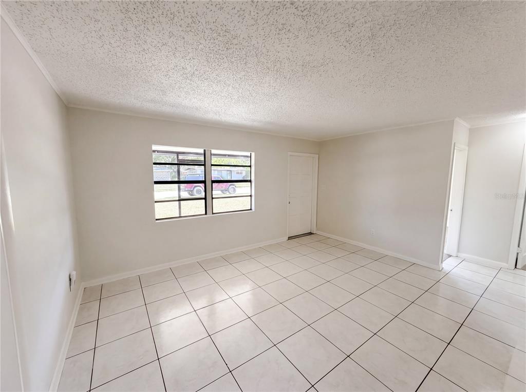An empty room features white tiled floors, light-colored walls, and a window with security bars — 459 NOTRE DAME DRIVE, ALTAMONTE SPRINGS, FL
