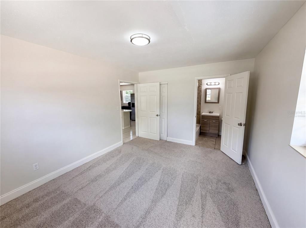 A carpeted bedroom features a ceiling light, a closet door, and an open bathroom door — 459 NOTRE DAME DRIVE, ALTAMONTE SPRINGS, FL